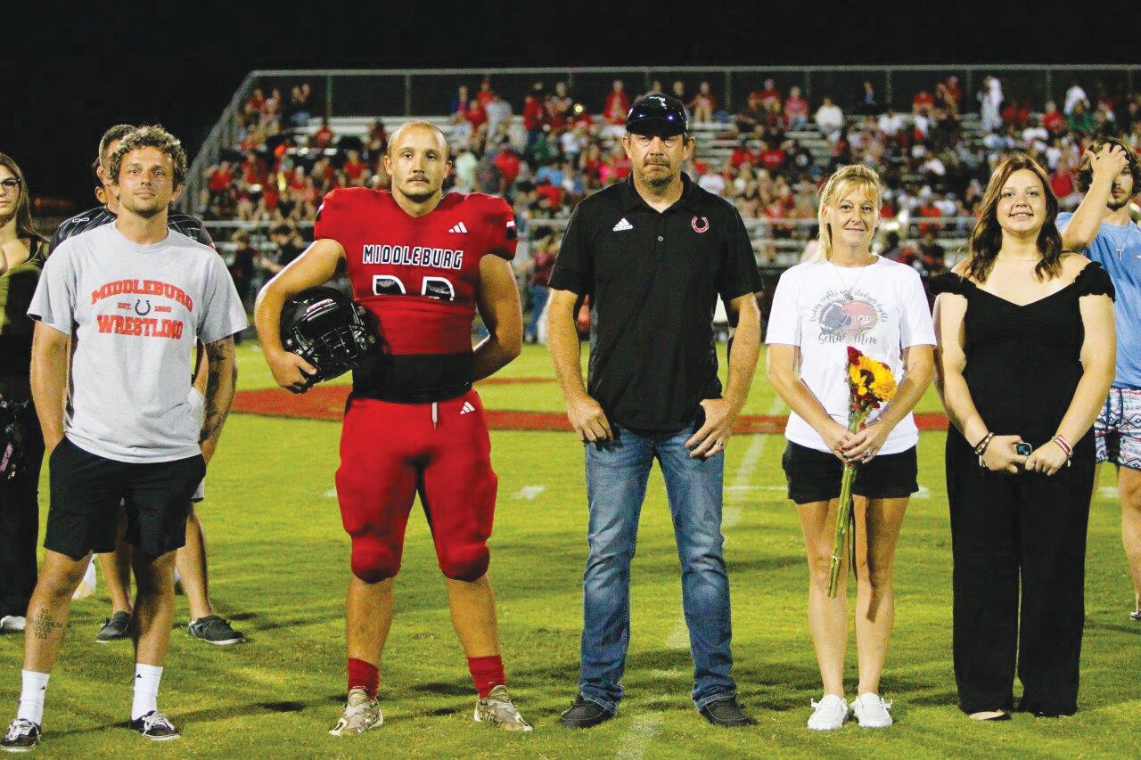 Middleburg linebacker Austin Cruce stands with parents and friends as sister Cheyenne Cruce gets her state wrestling championship ring during halftime ceremonies.